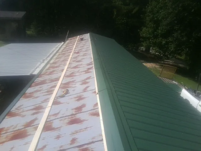 Old rusted panels beside newly installed green metal roofing — Wind Damage Roof Repair by Roofing Brothers in Rockledge